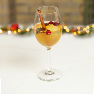 Maple Bourbon Punch served in wine glass with cinnamon stick garnish.